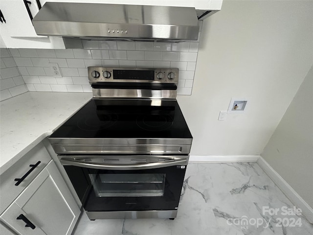 kitchen with backsplash, stainless steel electric stove, white cabinets, wall chimney exhaust hood, and light stone countertops