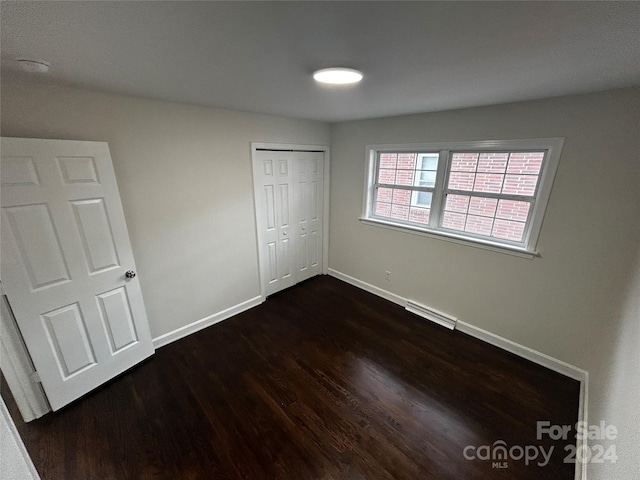 unfurnished bedroom with dark wood-type flooring and a closet