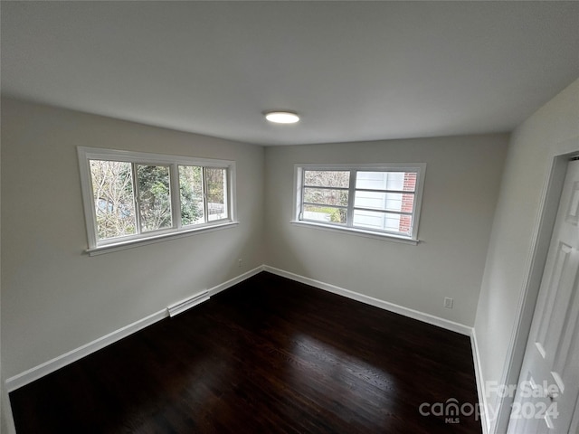 unfurnished room with baseboard heating and dark wood-type flooring