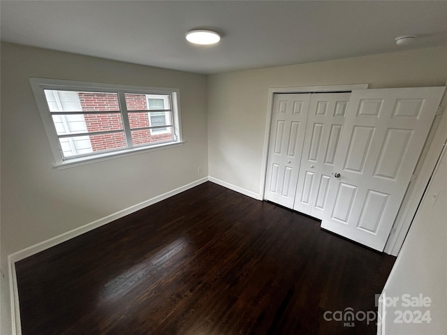 unfurnished bedroom featuring dark hardwood / wood-style floors and a closet