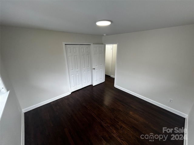 unfurnished bedroom featuring dark hardwood / wood-style floors and a closet