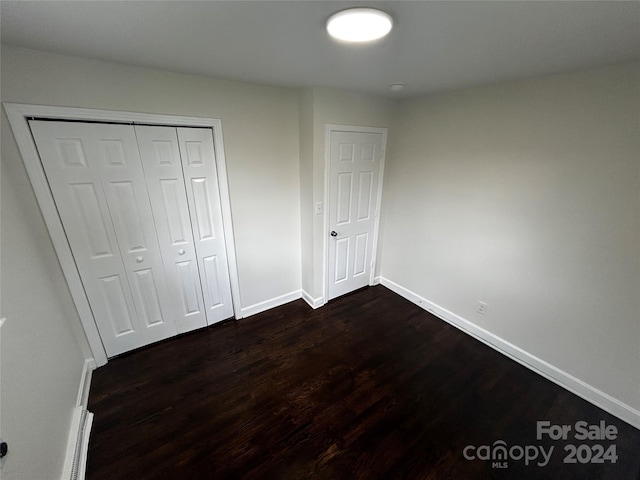 unfurnished bedroom with a closet and dark wood-type flooring