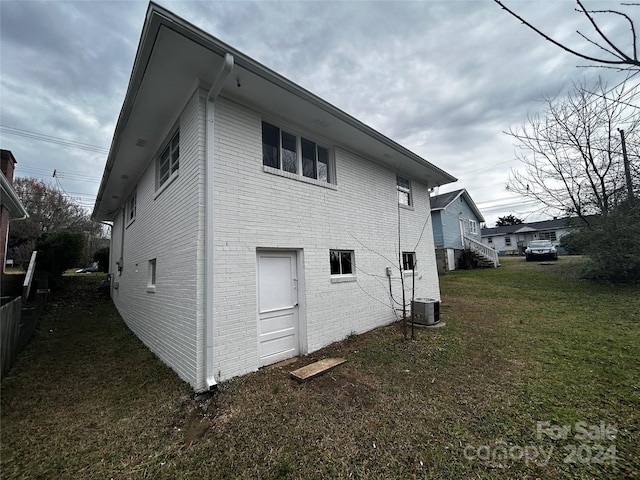 view of property exterior with a lawn and central AC unit