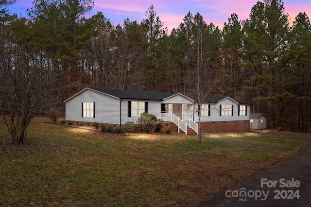 view of front of property featuring a lawn and a storage unit