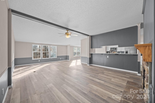 unfurnished living room featuring ceiling fan, wood-type flooring, and a textured ceiling