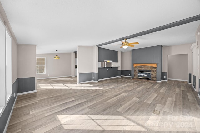 unfurnished living room featuring hardwood / wood-style flooring, a stone fireplace, and ceiling fan