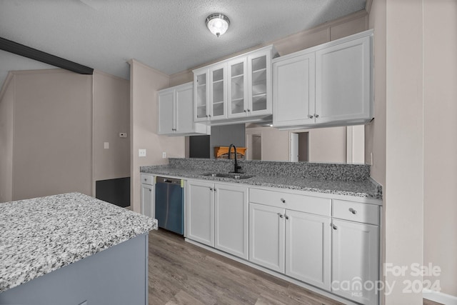 kitchen featuring light stone countertops, white cabinetry, sink, stainless steel dishwasher, and light hardwood / wood-style floors