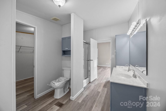 bathroom featuring vanity, wood-type flooring, an enclosed shower, and toilet