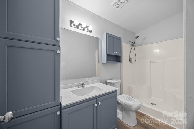 bathroom with a shower, wood-type flooring, vaulted ceiling, toilet, and vanity