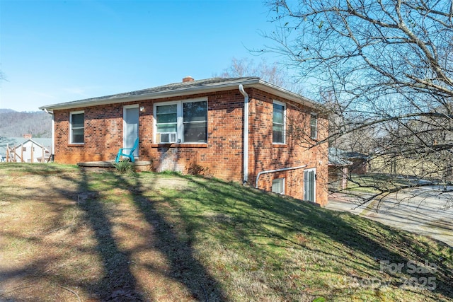 view of front of property with brick siding, a chimney, and a front yard