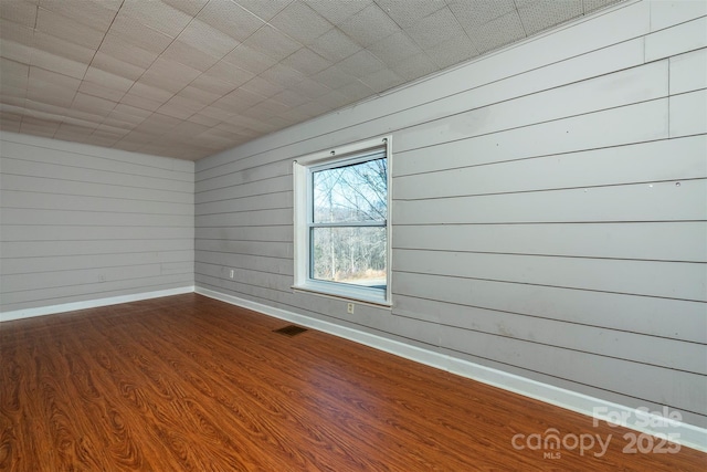 spare room featuring wood finished floors, baseboards, and visible vents