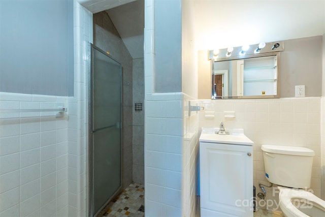 bathroom with a wainscoted wall, toilet, a tile shower, tile walls, and vanity