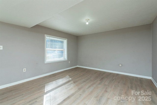 spare room featuring baseboards and light wood-style flooring