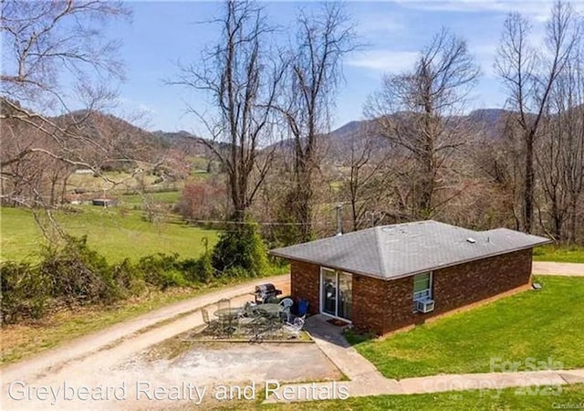 view of front of home with a mountain view, a front lawn, and driveway