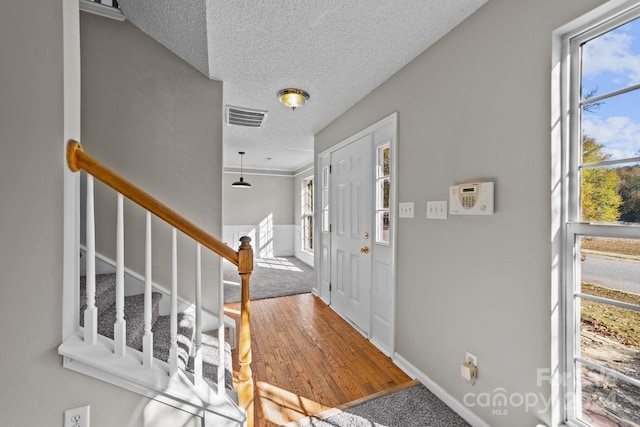 entrance foyer with a textured ceiling, hardwood / wood-style flooring, and ornamental molding