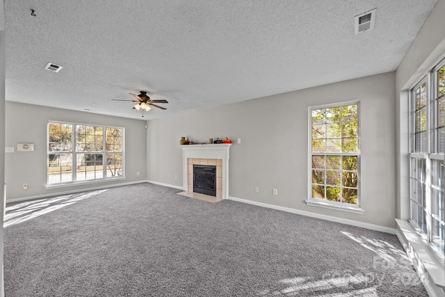 unfurnished living room featuring a tiled fireplace, a healthy amount of sunlight, and a textured ceiling