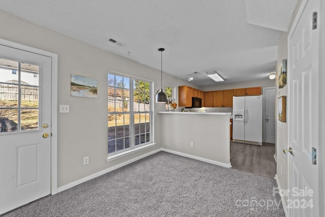 kitchen with pendant lighting, plenty of natural light, white refrigerator with ice dispenser, and carpet