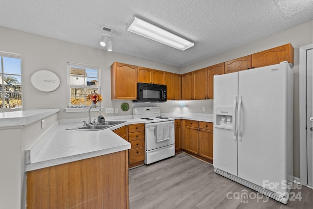 kitchen with a textured ceiling, light hardwood / wood-style flooring, white appliances, and sink