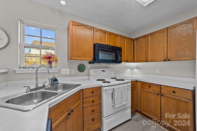 kitchen with electric range, light wood-type flooring, sink, and a textured ceiling