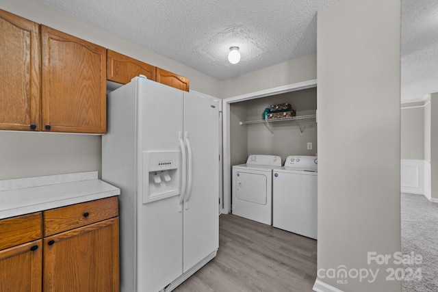 interior space featuring independent washer and dryer, white fridge with ice dispenser, a textured ceiling, and light wood-type flooring