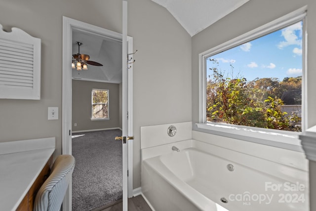 bathroom with a tub to relax in, vaulted ceiling, a wealth of natural light, and ceiling fan