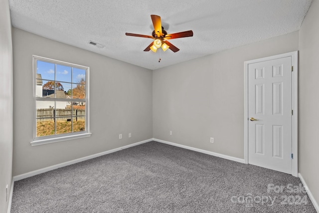 unfurnished room with carpet flooring, ceiling fan, and a textured ceiling