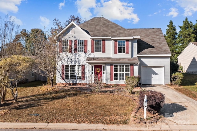 colonial inspired home featuring a garage and a front lawn