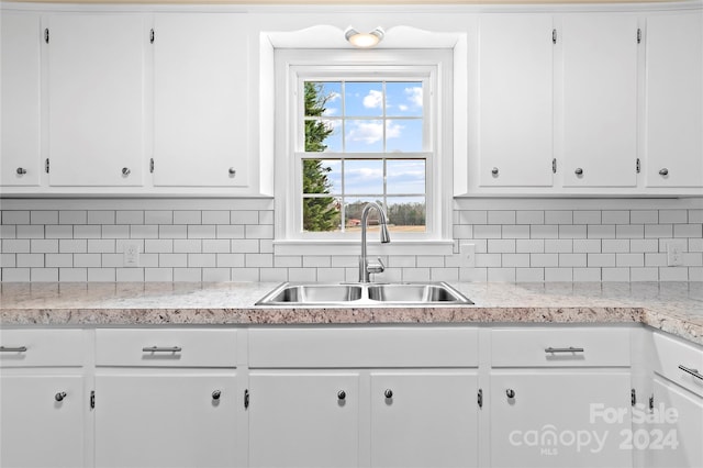 kitchen featuring backsplash, white cabinetry, and sink