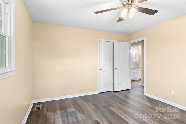 unfurnished bedroom featuring ceiling fan, a closet, a textured ceiling, and hardwood / wood-style flooring