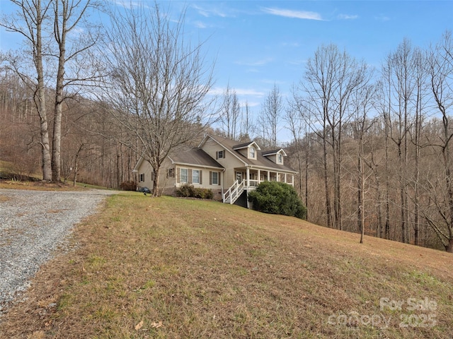 cape cod home with a front lawn, a porch, and gravel driveway