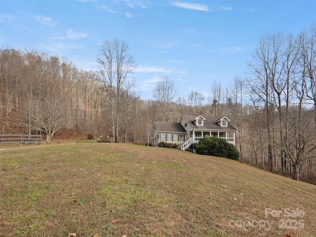 exterior space featuring a wooded view, a front yard, and fence