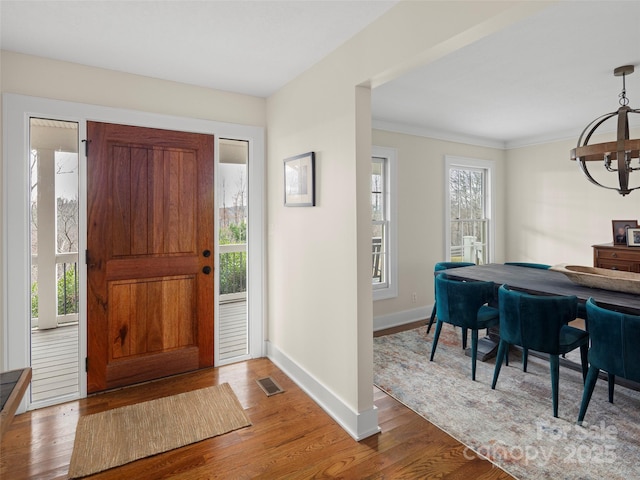 entrance foyer featuring baseboards, wood finished floors, visible vents, and a healthy amount of sunlight