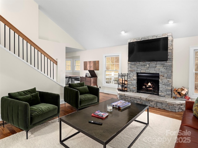 living room featuring stairs, lofted ceiling, a fireplace, and wood finished floors