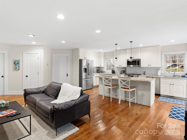 living area featuring recessed lighting, baseboards, and light wood finished floors