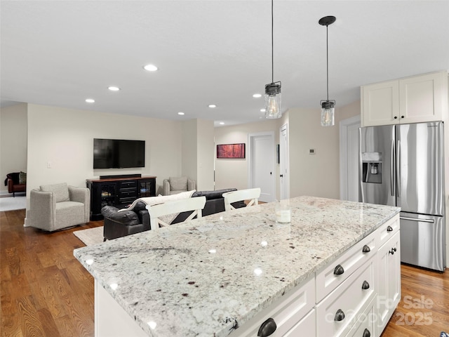 kitchen with recessed lighting, light wood-style flooring, white cabinetry, light stone countertops, and stainless steel fridge with ice dispenser