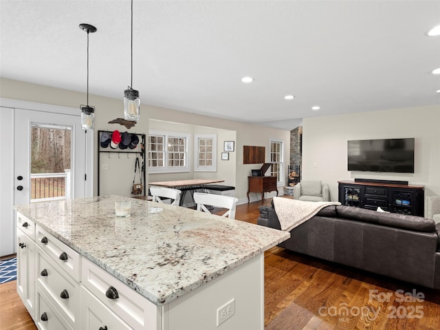 kitchen featuring light wood-type flooring, light stone counters, and white cabinets