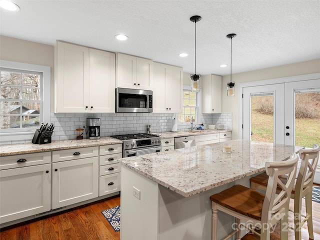 kitchen featuring decorative backsplash, dark wood finished floors, a kitchen island, a breakfast bar area, and stainless steel appliances