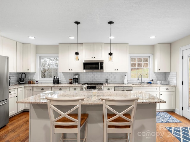 kitchen featuring appliances with stainless steel finishes, light wood-type flooring, a sink, and a center island