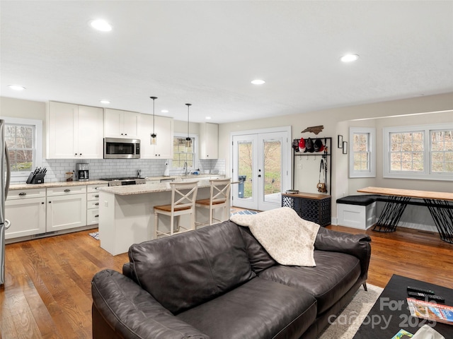 living area featuring french doors, light wood-type flooring, and recessed lighting