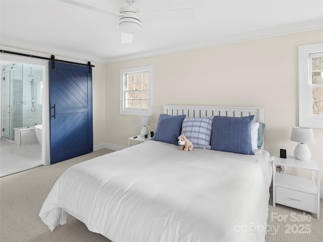 bedroom featuring carpet floors, crown molding, ensuite bathroom, a barn door, and baseboards