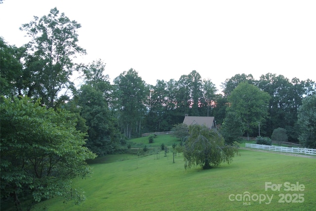 view of yard with fence and a rural view