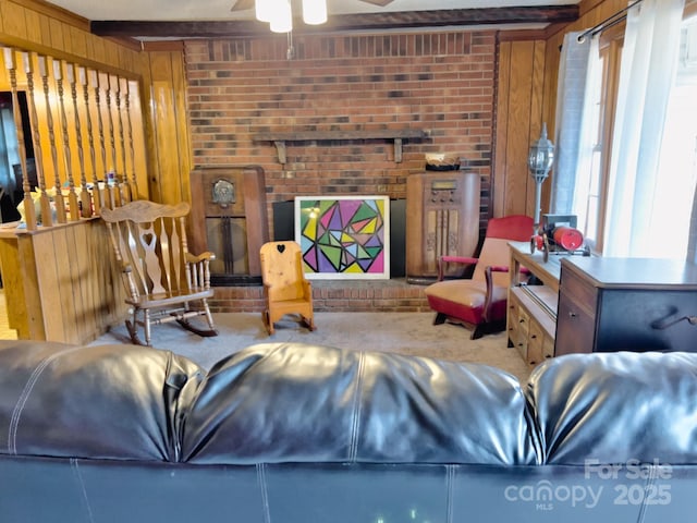 carpeted living room with ceiling fan, beam ceiling, brick wall, and wooden walls