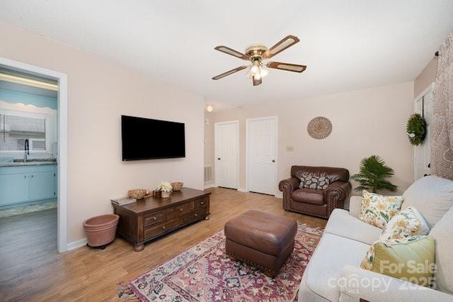 living room featuring hardwood / wood-style floors, sink, and ceiling fan