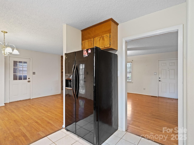 kitchen with light tile patterned flooring, a chandelier, black refrigerator with ice dispenser, and a textured ceiling