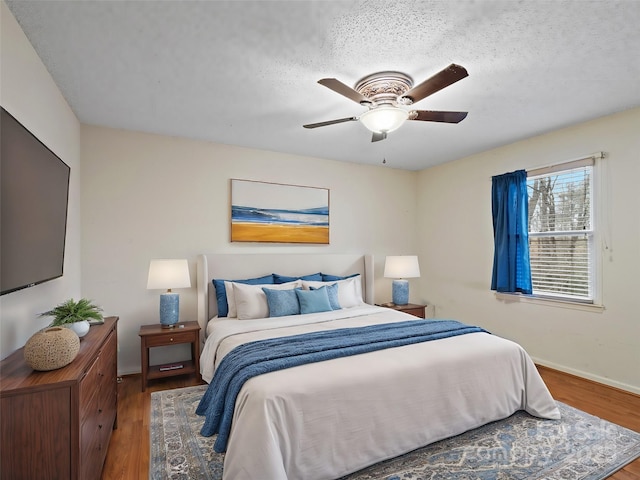 bedroom featuring ceiling fan, hardwood / wood-style floors, and a textured ceiling