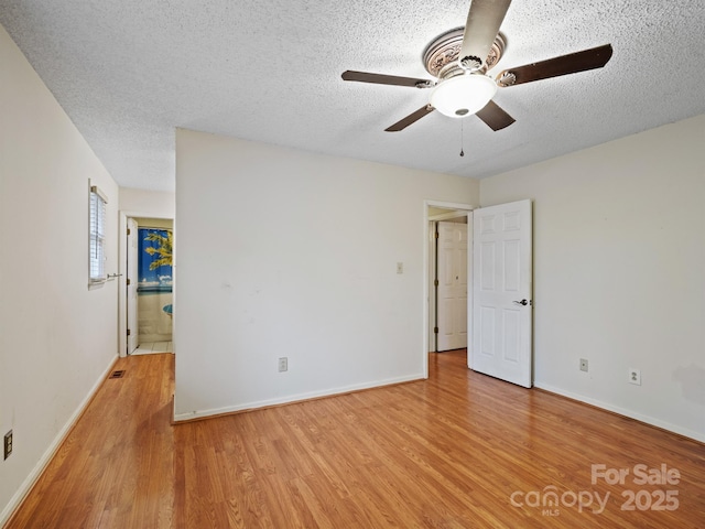 empty room with ceiling fan, light hardwood / wood-style flooring, and a textured ceiling