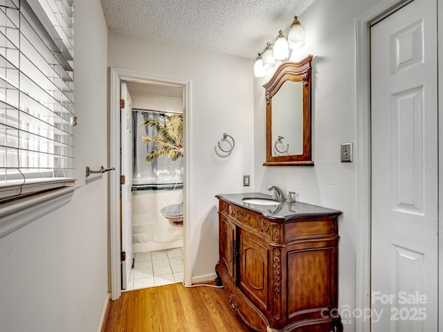 bathroom with hardwood / wood-style flooring, vanity, a shower with curtain, and a textured ceiling