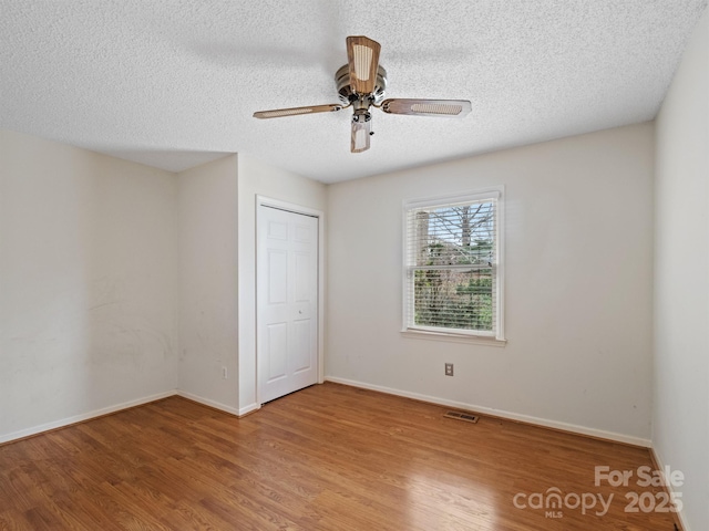 unfurnished room with wood-type flooring, ceiling fan, and a textured ceiling