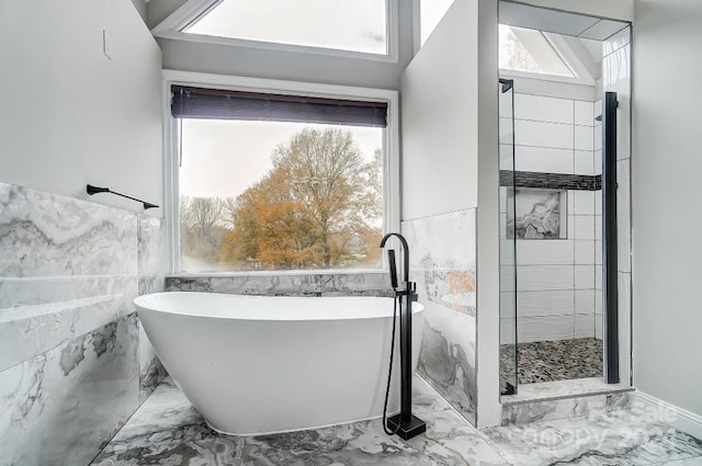 bathroom with a bathtub, a healthy amount of sunlight, and tile walls