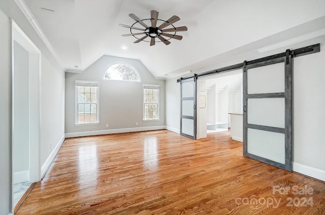 interior space featuring lofted ceiling, a barn door, light wood-type flooring, and ceiling fan